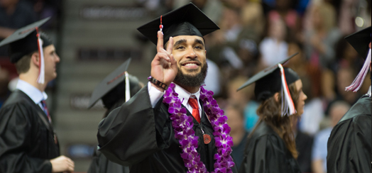 graduating man holds up a peace sign